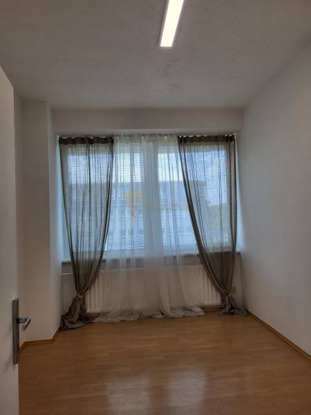 Kancelárie, Drieňová ul., Ružinov 25 m2 - Svetlá miestnosť s drevenou podlahou a veľkým oknom so závesmi v Kancelárii.