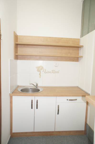 Kancelárie, Drieňová ul., Ružinov 25 m2 - Malá kuchynka s drezom a poličkami bez dekorácií v kancelárii.