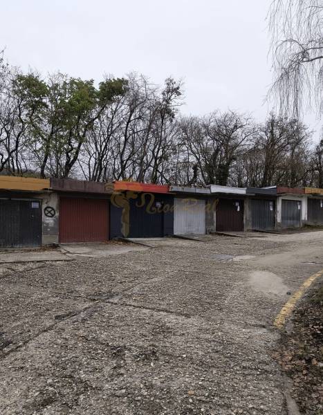 Garáž Púpavova, Karlova Ves + pivnica - Staršie garáže pri Púpavovej ulici, pokryté stromami a prázdnou cestou.