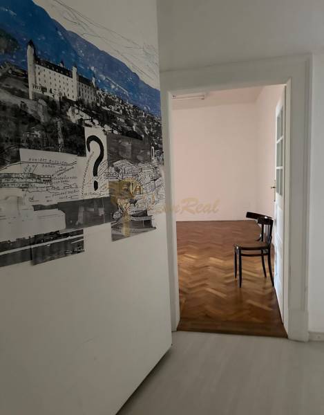 3,5 izb. byt v priamo centre Bratislavy na pešej zóne - Interiér 4-izbového bytu s podlahou s dreveným dekorom a umeleckou výzdobou na stene.