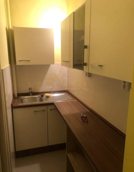 1-izb. byt na ul. Račianska, Nové Mesto s lodžiou - Kuchynský kútik s dreveným dekorom a bielymi skrinkami v 1-izbovom byte.