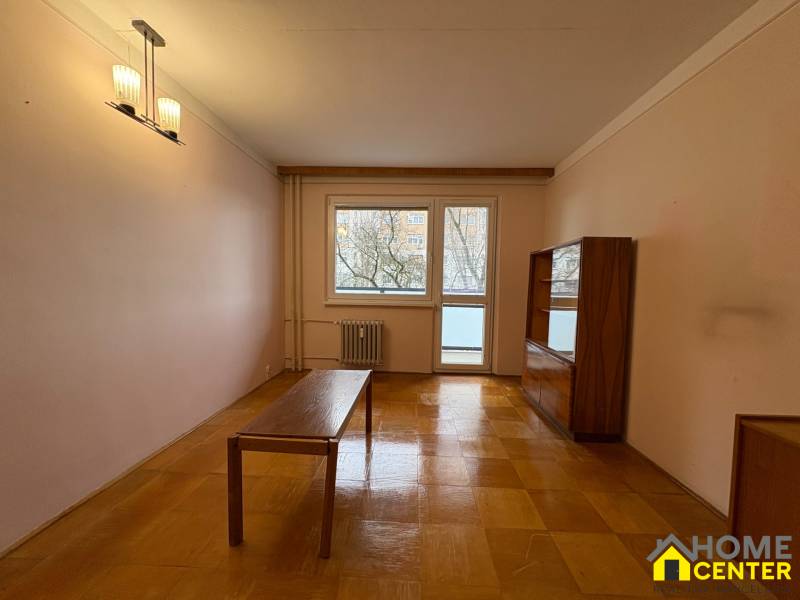 R E Z E R V O V A N Ý 3 izbový byt s balkónom , Košická, Komárno - Obývacia izba v 3-izbovom byte s podlahou s dreveným dekorom a jednoduchým nábytkom.