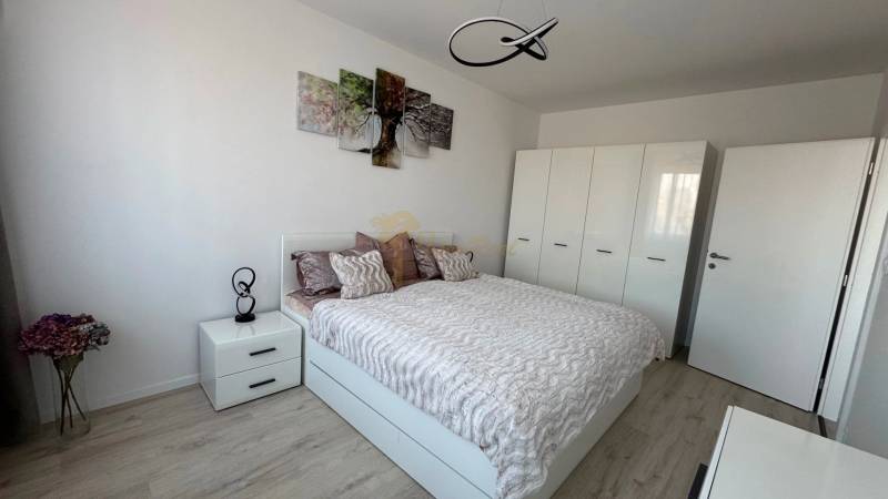 Novostavba 2,5-izb. bytu v NUPPU, garážové státie + vonkajšie státie - Spálňa v 2-izbovom byte s posteľou, skriňou a podlahou s dreveným dekorom.