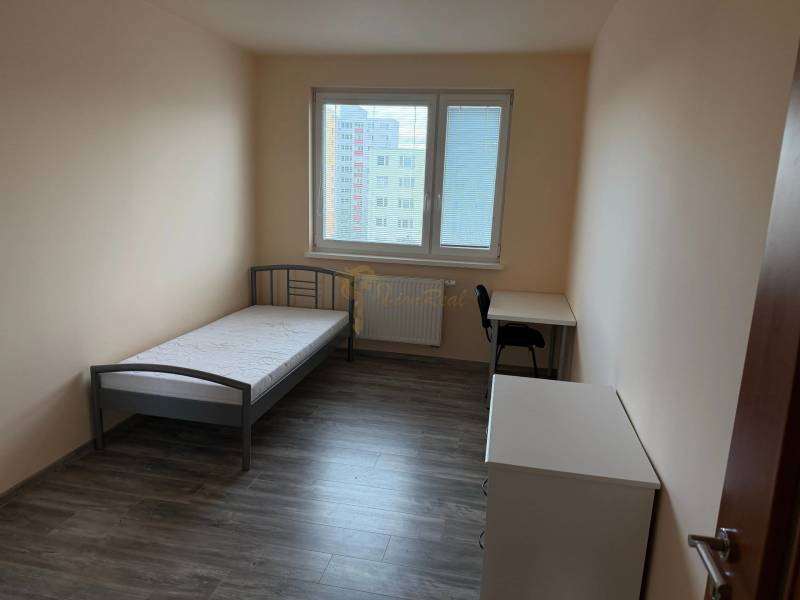 4-izb. byt, Wolkrova, Petržalka, 7.p./8 - Svetlá izba v 4-izbovom byte s posteľou, stolom a podlahou s dreveným dekorom.