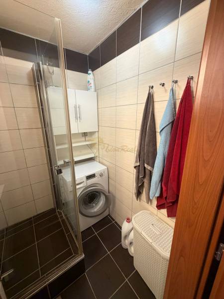 4-izb. byt, Wolkrova, Petržalka, 7.p./8 - Kúpeľňa v 4-izbovom byte s práčkou, sprchovým kútom, uterákmi a košom na bielizeň.