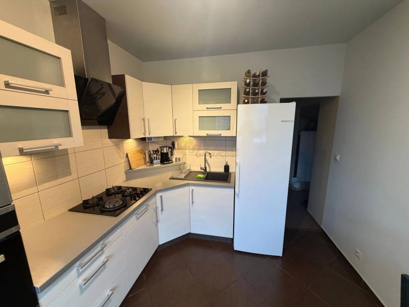 4-izb. byt, Wolkrova, Petržalka, 7.p./8 - Kuchyňa v 4-izbovom byte s bielymi skrinkami a tmavou podlahou s dreveným dekorom.