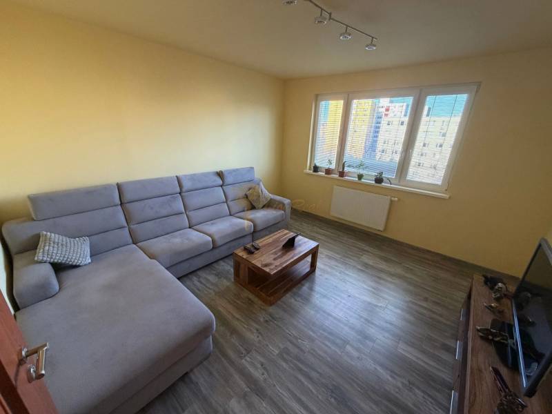 4-izb. byt, Wolkrova, Petržalka, 7.p./8 - Obývačka v 4-izbovom byte s pohovkou, konferenčným stolíkom a podlahou s dreveným dekorom.