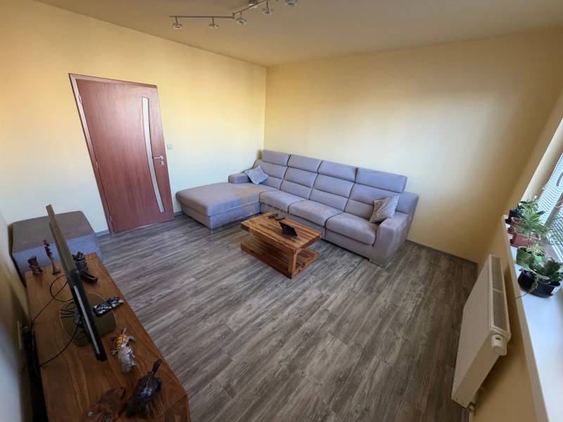 4-izb. byt, Wolkrova, Petržalka, 7.p./8 - Obývačka so sedačkou, TV stolíkom a podlahou s dreveným dekorom v 4-izbovom byte.