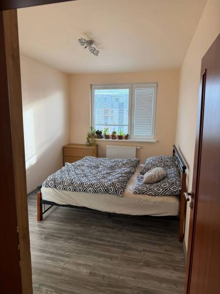 4-izb. byt, Wolkrova, Petržalka, 7.p./8 - Spálňa v 4-izbovom byte s posteľou a podlahou s dreveným dekorom.