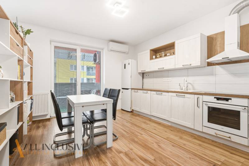 Na predaj moderný 2-izb. byt s loggiou vo Vrábľoch - Kuchyňa v 2-izbovom byte s bielymi skriňami a podlahou s dreveným dekorom.