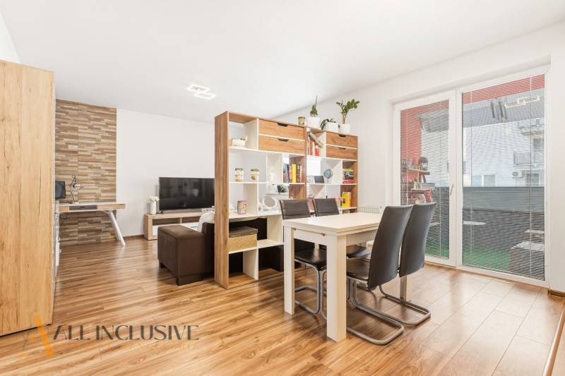 Na predaj moderný 2-izb. byt s loggiou vo Vrábľoch - Obývačka s jedálenským stolom v 2-izbovom byte, podlaha s dreveným dekorom, knižnica.