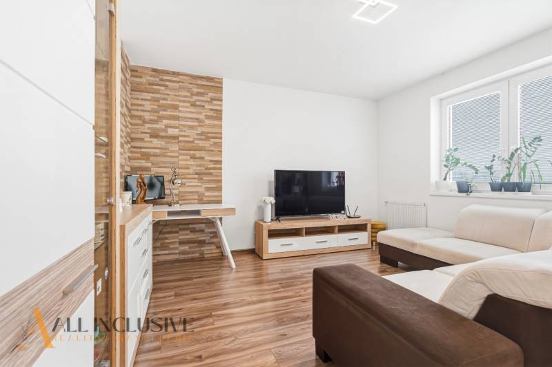 Na predaj moderný 2-izb. byt s loggiou vo Vrábľoch - Obývacia izba s podlahou s dreveným dekorom, TV a krémovou sedačkou v 2-izbovom byte.