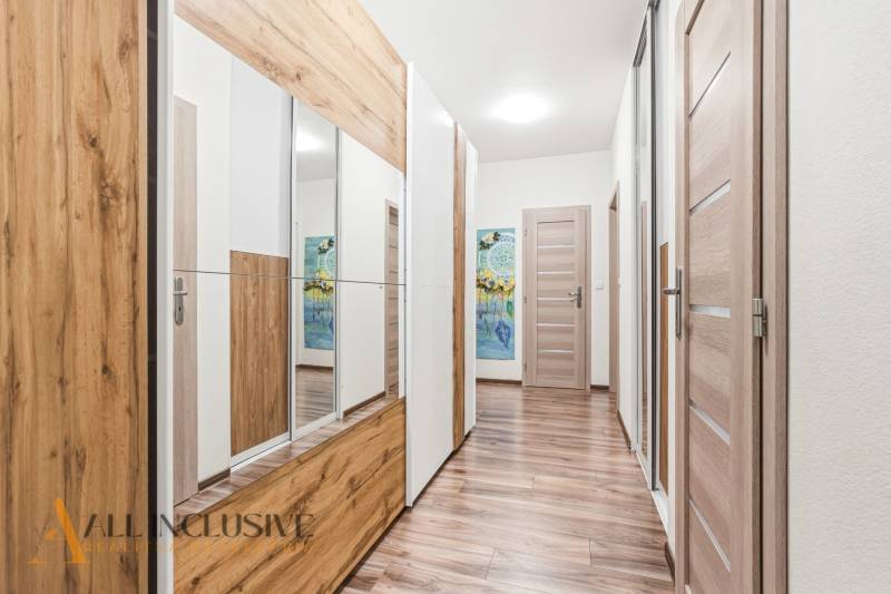 Na predaj moderný 2-izb. byt s loggiou vo Vrábľoch - Chodba v 2-izbovom byte s podlahou s dreveným dekorom a zrkadlovou skriňou.