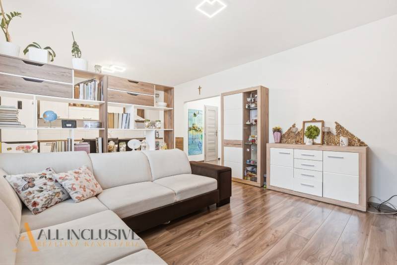 Na predaj moderný 2-izb. byt s loggiou vo Vrábľoch - Obývačka 2-izbového bytu s béžovou sedačkou a podlahou s dreveným dekorom.