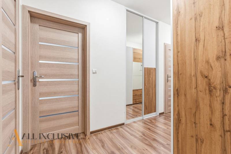 Na predaj moderný 2-izb. byt s loggiou vo Vrábľoch - Chodba v 2-izbovom byte s podlahou s dreveným dekorom a zrkadlovou skriňou.