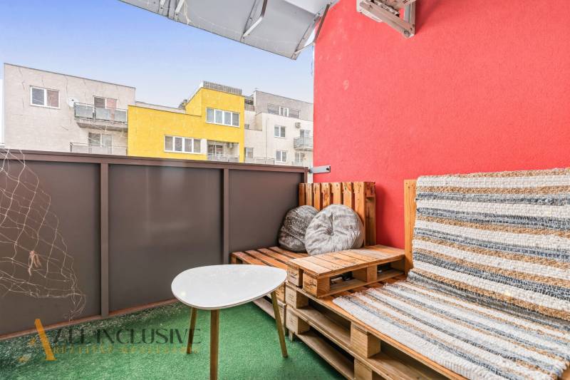 Na predaj moderný 2-izb. byt s loggiou vo Vrábľoch - Balkón s paletovým nábytkom a stolíkom, farbené budovy vo Vrábľoch, 2-izbový byt.