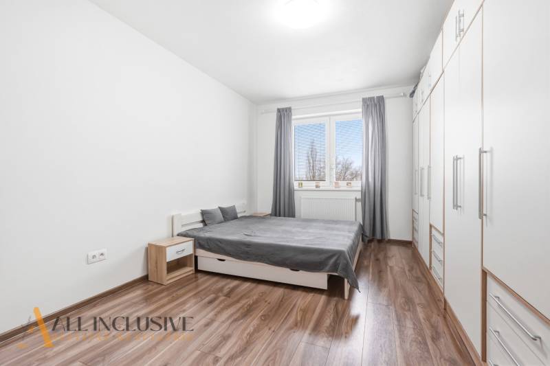 Na predaj moderný 2-izb. byt s loggiou vo Vrábľoch - Spálňa v 2-izbovom byte s podlahou s dreveným dekorom, bielymi skriňami a sivými detailmi.