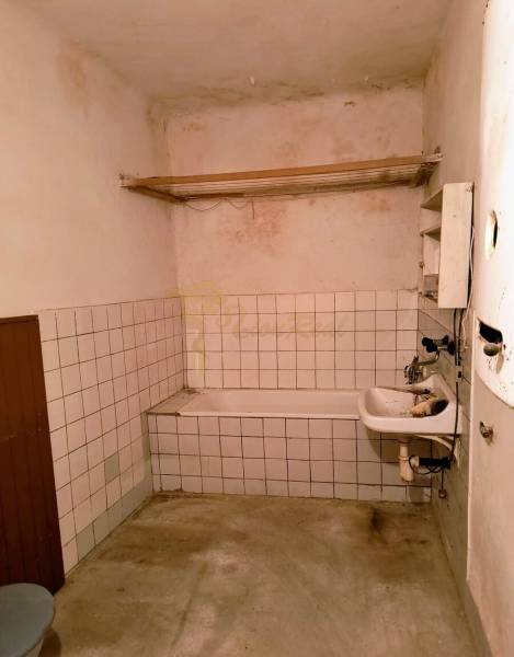 Rodinný dom Svätý Jur, centrum, pôvodný stav - Kúpeľňa v rodinnom dome s jednoduchou vaňou, umývadlom a dlaždicovými stenami.