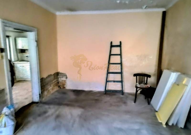 Rodinný dom Svätý Jur, centrum, pôvodný stav - Miestnosť v rodinnom dome s rebríkom, stoličkou a materiálmi na podlahe s dreveným dekorom.