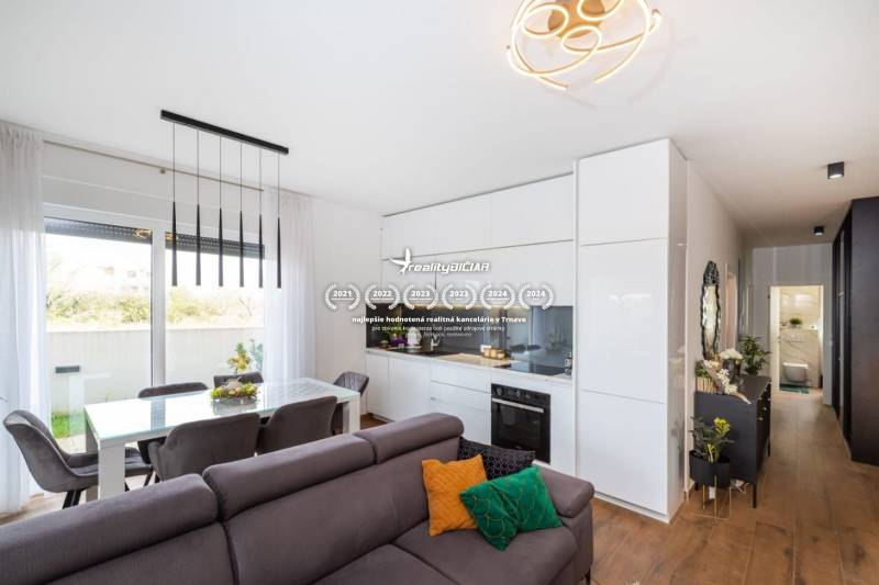 ZATON - Apartmán so záhradou - na predaj  - Obývačka a kuchyňa Rekreačného apartmánu s podlahou s dreveným dekorom a jedálenským kútom.