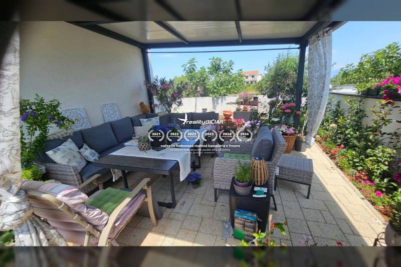 ZATON - Apartmán so záhradou - na predaj  - Relaxácia na terase v Rekreačnom apartmáne s pohodlným sedením, kvetinovou výzdobou a stolom.