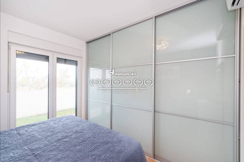 ZATON - Apartmán so záhradou - na predaj  - Spálňa v rekreačnom apartmáne s veľkou vstavanou skriňou a posteľou s modrou prikrývkou.