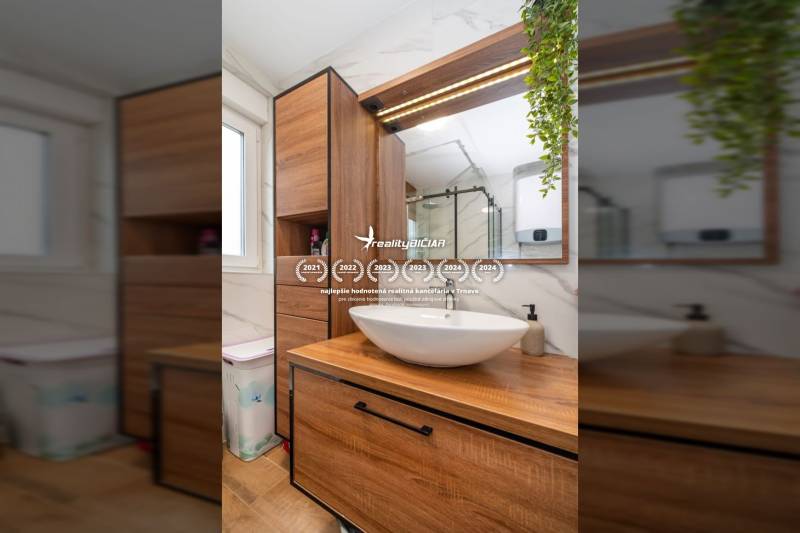 ZATON - Apartmán so záhradou - na predaj  - Kúpeľňa v rekreačnom apartmáne s umývadlom, dreveným nábytkom a podlahou s dreveným dekorom.