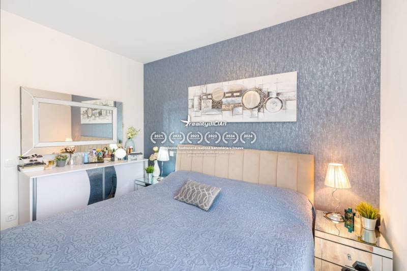 ZATON - Apartmán so záhradou - na predaj  - Spálňa v Rekreačnom apartmáne s modrým prehozom, dekoráciami a zrkadlom nad stolíkom.