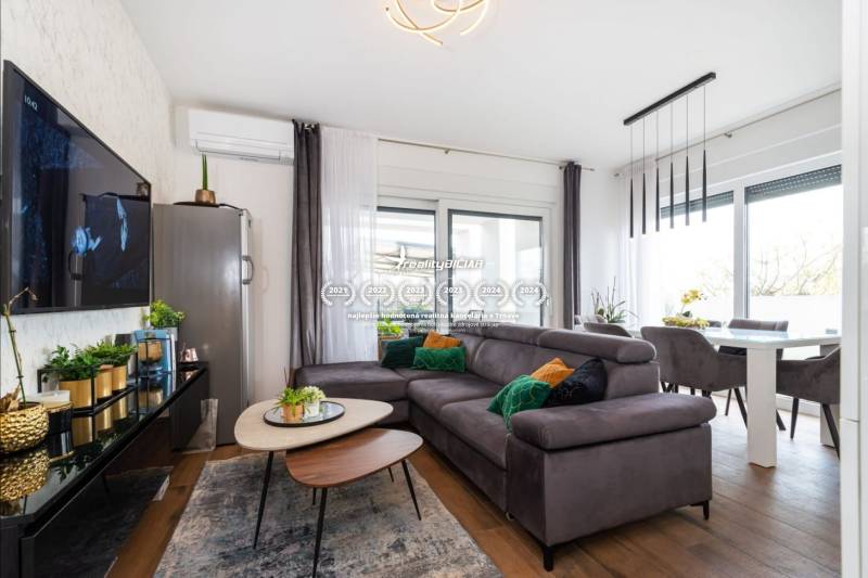 ZATON - Apartmán so záhradou - na predaj  - Obývacia izba v Rekreačnom apartmáne s pohodlnou sedačkou a podlahou s dreveným dekorom.