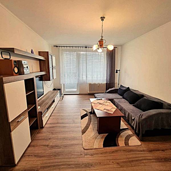 Pekný 2 izbový byt na prenájom - Malacky - Obývacia izba v 2-izbovom byte s podlahou s dreveným dekorom a pohovkou.