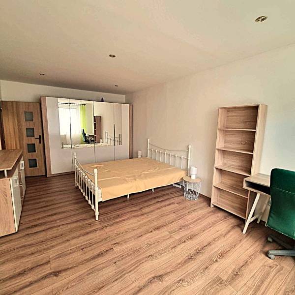 Pekný 2 izbový byt na prenájom - Malacky - Spálňa v 2-izbovom byte s posteľou, skriňou a podlahou s dreveným dekorom.