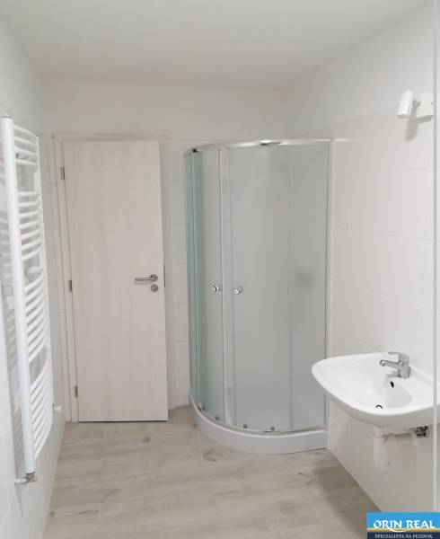 Na predaj kompletne zrekonštruovaný RD Bernolákovo -Trnavská - Kúpeľňa v rodinnom dome s bielym sprchovacím kútom a svetlou podlahou s dreveným dekorom.