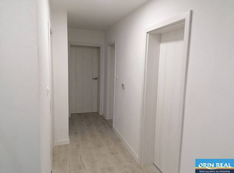 Na predaj kompletne zrekonštruovaný RD Bernolákovo -Trnavská - Chodba v rodinnom dome s bielymi stenami a podlahou s dreveným dekorom.