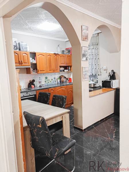 Rodinný dom, Maďarsko, obec Vizsoly - Kuchyňa v rodinnom dome s oblúkovým vstupom, drevené skrinky a čierne podlahy.