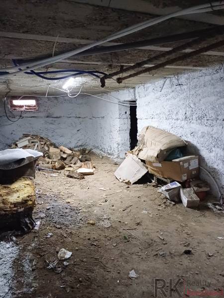 Rodinný dom, Maďarsko, obec Vizsoly - Suterén rodinného domu s hlinenou podlahou, niekoľkými krabicami a drevom.