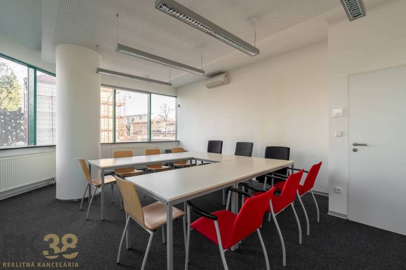 Reprezentatívne administratívne priestory na prenájom  - Interiér kancelárie s dlhým stolom, farebnými stoličkami a veľkými oknami.