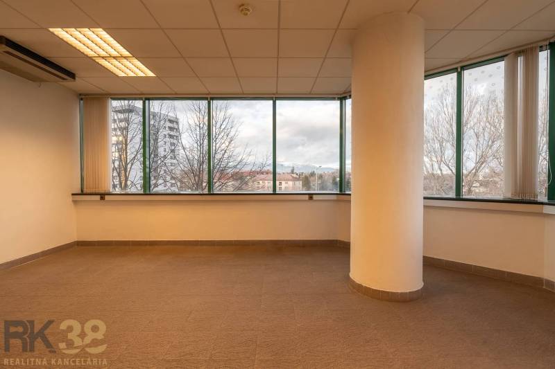 Reprezentatívne administratívne priestory na prenájom  - Interiér kancelárií s veľkými oknami a stĺpom, podlaha s dreveným dekorom.