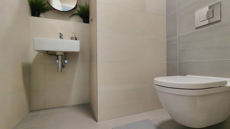 NUERA︱SKY PARK Moderný 2-izbový byt na 6. poschodí, veža 3 - Kúpeľňa 2-izbového bytu so zavesenou toaletou, umývadlom a bielymi kachličkami.