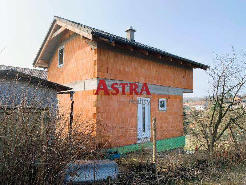 CHATA UZAVRETÁ HRUBÁ STAVBA, KOŠICKÁ NOVÁ VES - GEDER - Chata v výstavbe s tehlovými stenami pri dedine a záhrady na pozadí.