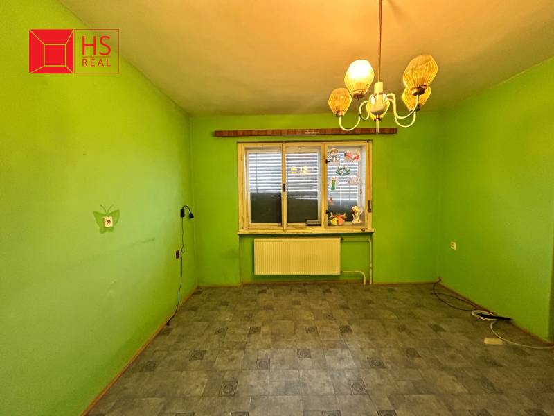 Predaj staršieho RD vo Dvoroch nad Žitavou - Izba v rodinnom dome so zelenými stenami, lampou a podlahou s dreveným dekorom.