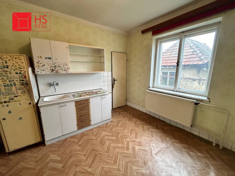 Predaj staršieho RD vo Dvoroch nad Žitavou - Kuchyňa v rodinnom dome s podlahou s dreveným dekorom a jednoduchou kuchynskou linkou.