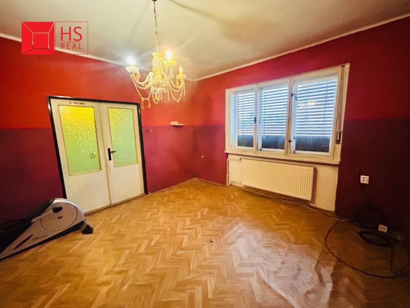 Predaj staršieho RD vo Dvoroch nad Žitavou - Izba v rodinnom dome s lustrom a podlahou s dreveným dekorom.