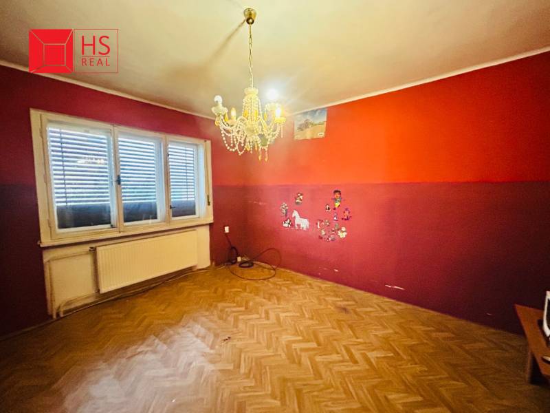 Predaj staršieho RD vo Dvoroch nad Žitavou - Miestnosť v rodinnom dome s lustrom, podlaha s dreveným dekorom a farebnými stenami.
