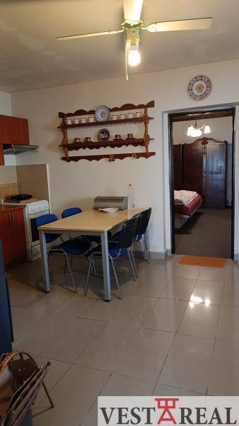 Na Predaj Rodinný dom pozemok 1587 m² v Horných Salibách  - Jedálenský stôl so stoličkami v rodinnom dome, kuchynská časť a otvorené dvere do spálne.