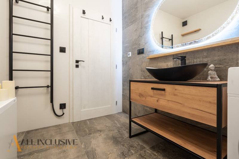 Rezervované 3-izbový byt so záhradou, Šamorín - Kúpeľňa s podlahou s dreveným dekorom, umývadlom a zrkadlom v 3-izbovom byte.