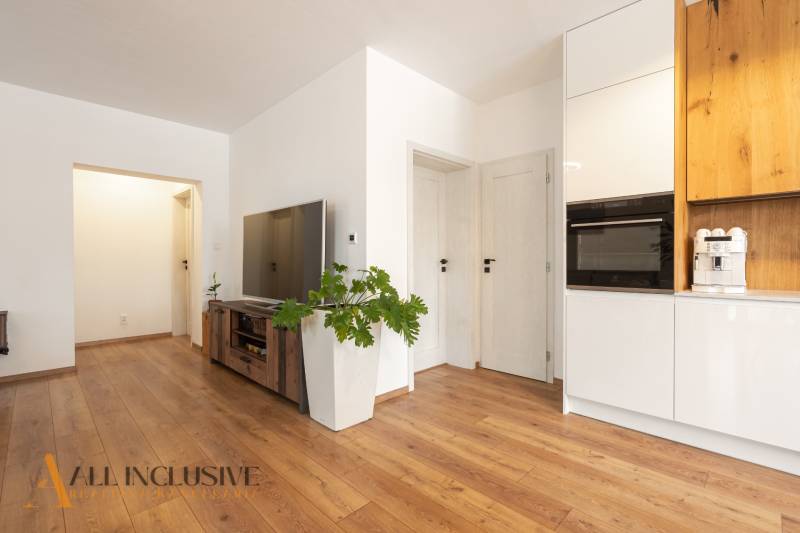 Rezervované 3-izbový byt so záhradou, Šamorín - Obývacia izba v 3-izbovom byte, podlaha s dreveným dekorom, biele steny, televízor.