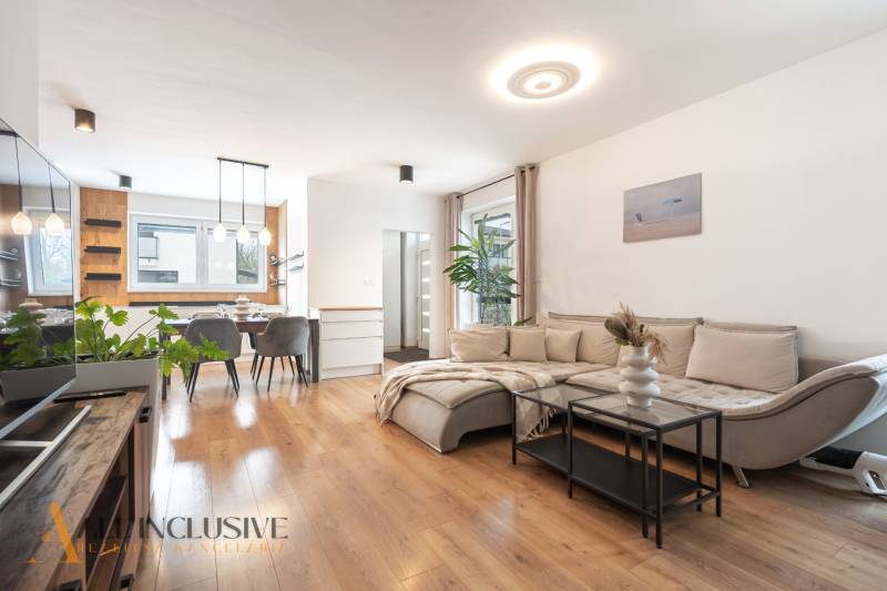 Rezervované 3-izbový byt so záhradou, Šamorín - Obývačka v 3-izbovom byte s pohovkou, jedálenským stolom a podlahou s dreveným dekorom.