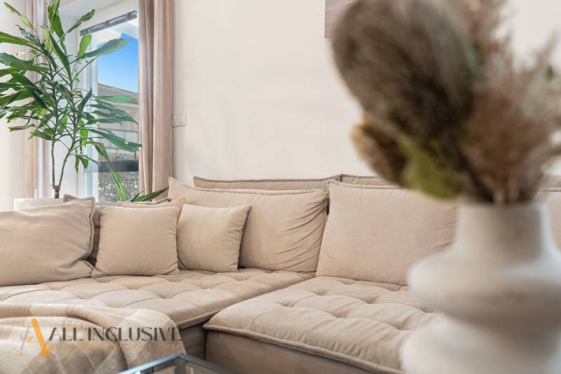 Rezervované 3-izbový byt so záhradou, Šamorín - Pohodlná pohovka s béžovými vankúšmi a zelenou rastlinou v 3-izbovom byte.