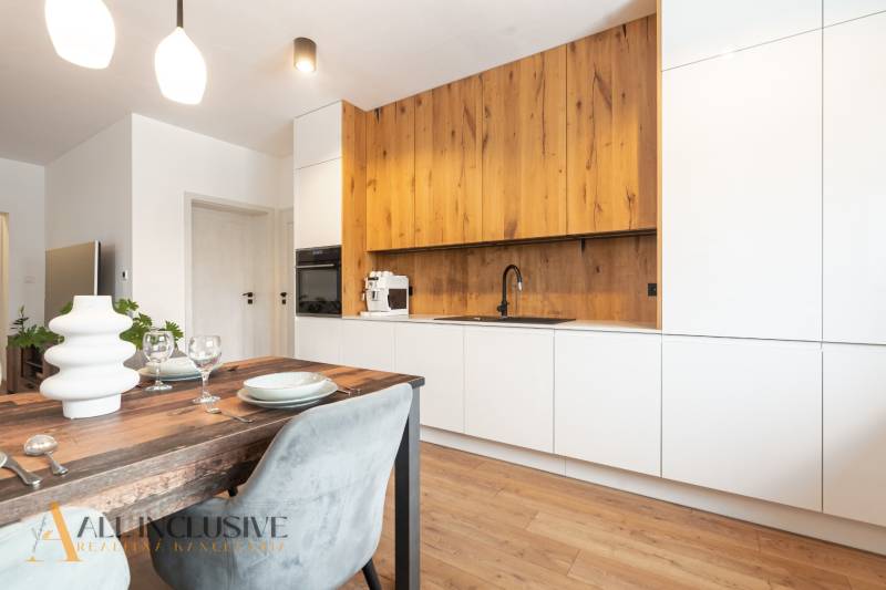 Rezervované 3-izbový byt so záhradou, Šamorín - Kuchyňa s bielymi skriňami a podlahou s dreveným dekorom v 3-izbovom byte.