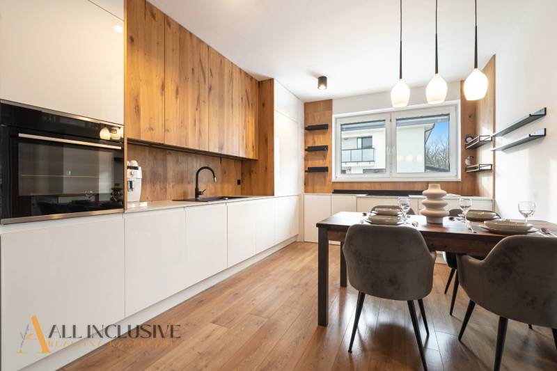 Rezervované 3-izbový byt so záhradou, Šamorín - Kuchyňa v 3-izbovom byte s podlahou s dreveným dekorom, jedálenským stolom a veľkým oknom.